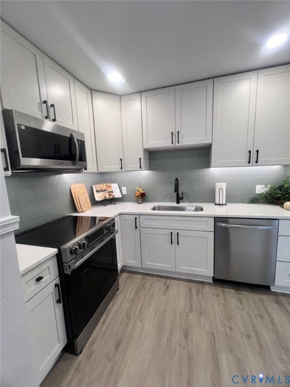 404 Ivey Avenue, Woodlawn, Colonial Heights, VA 23834 Kitchen featuring white cabinetry with matte black hardware, light-toned stone-finish countertops, tiled backsplash, stainless steel appliances, and wood-finish flooring