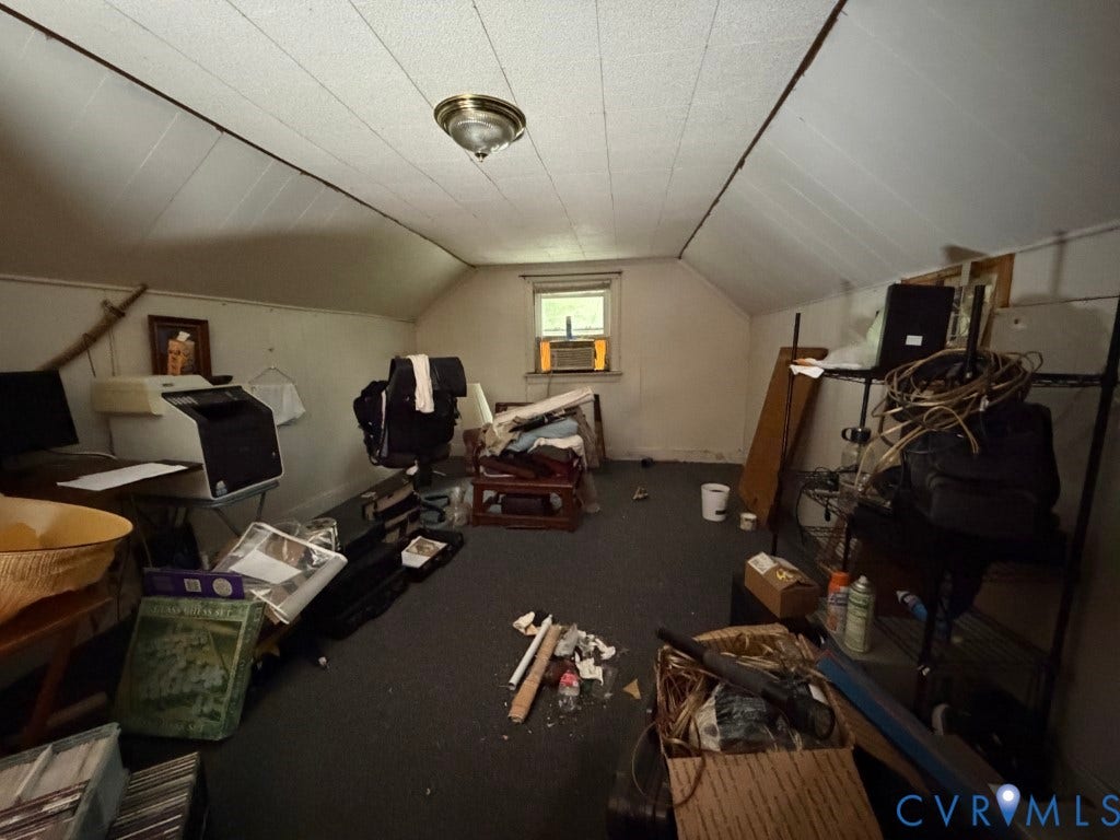 Sloped ceiling room featuring wall-to-wall carpeting, a center-mounted flush mount light fixture, and a single exterior-facing window