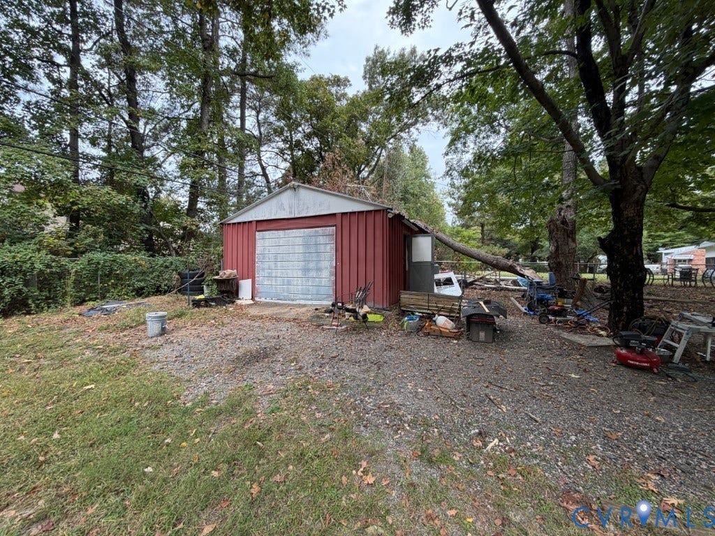 Detached metal-sided structure featuring a single-car garage door and a gravel exterior surface
