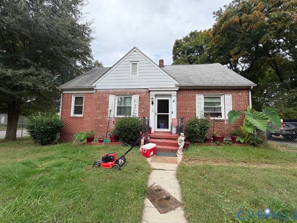 Traditional brick exterior featuring a gable roof, white-trimmed windows with shutters, and a concrete walkway