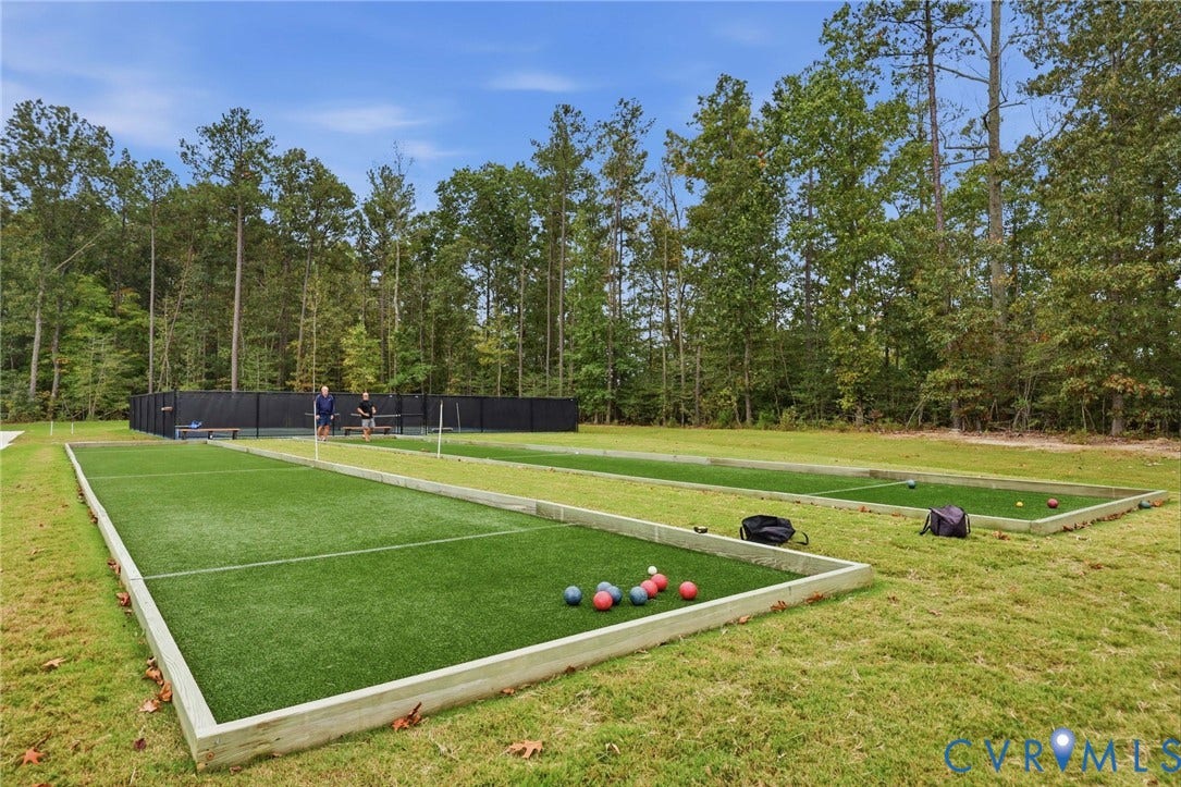 Dual synthetic turf bocce ball courts featuring timber framing and a perimeter black sports netting enclosure