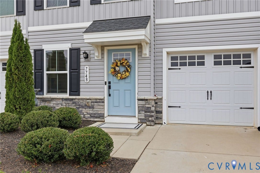 Exterior featuring horizontal siding, stone veneer accents, a covered front entryway, and a single-car garage with decorative hardware and window panels