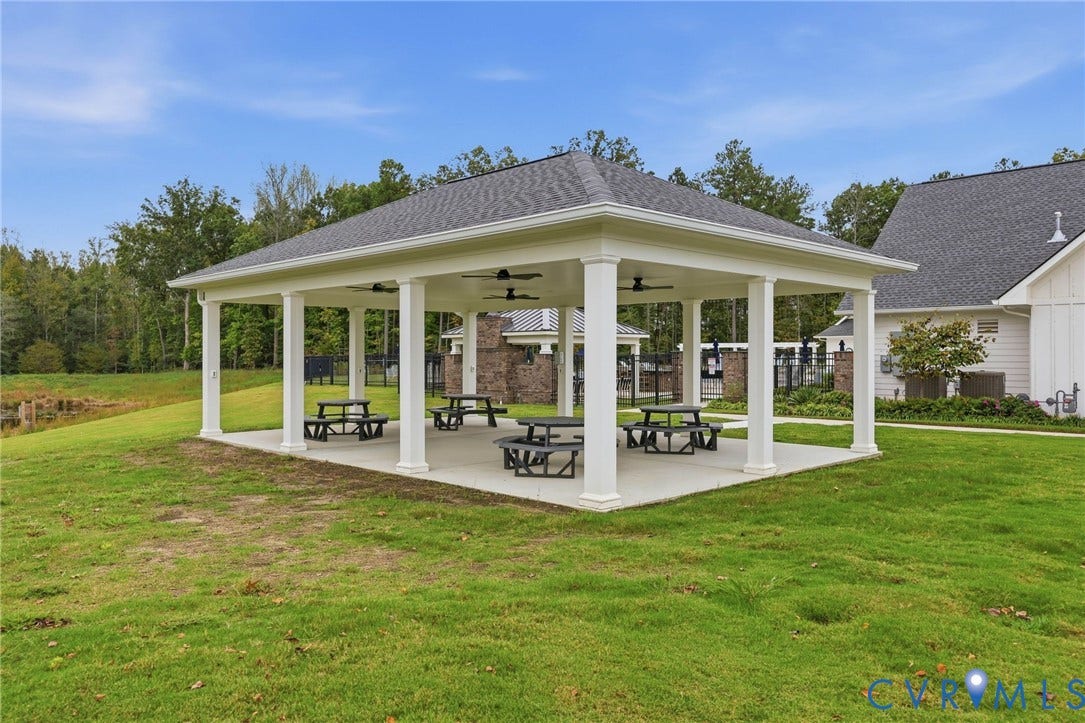 Covered pavilion featuring a concrete pad, square columns, a hipped roof, and overhead ceiling fans