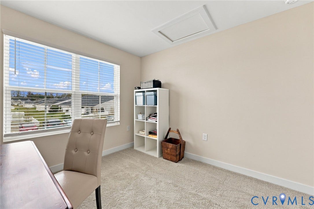 Neutral-toned room featuring wall-to-wall carpeting and a large window with horizontal blinds