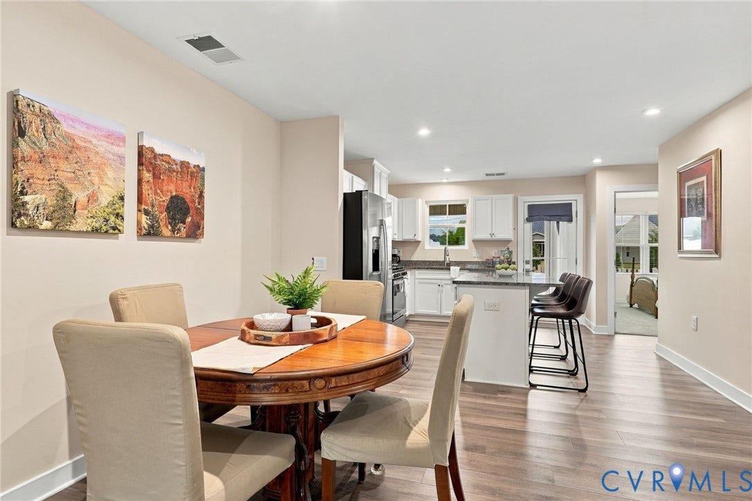 Kitchen featuring white cabinetry, stone countertops, a center island with seating, stainless steel appliances, and wood-finish flooring