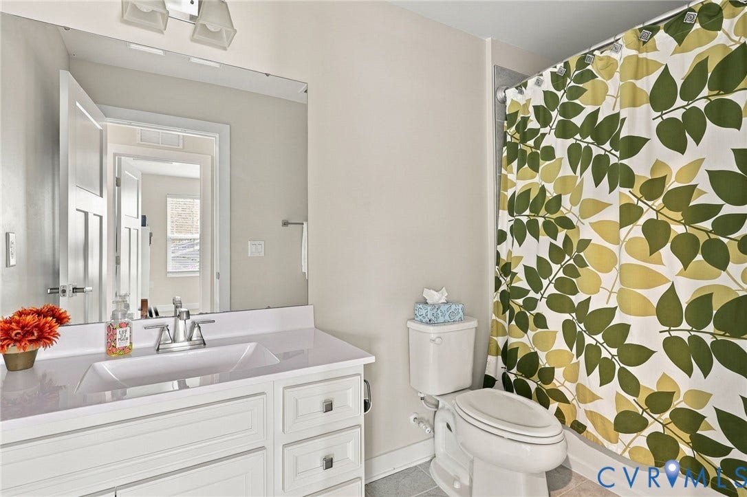 Bathroom featuring a white vanity cabinet, integrated sink with a chrome faucet, wall-mounted mirror, and a tub-shower combination
