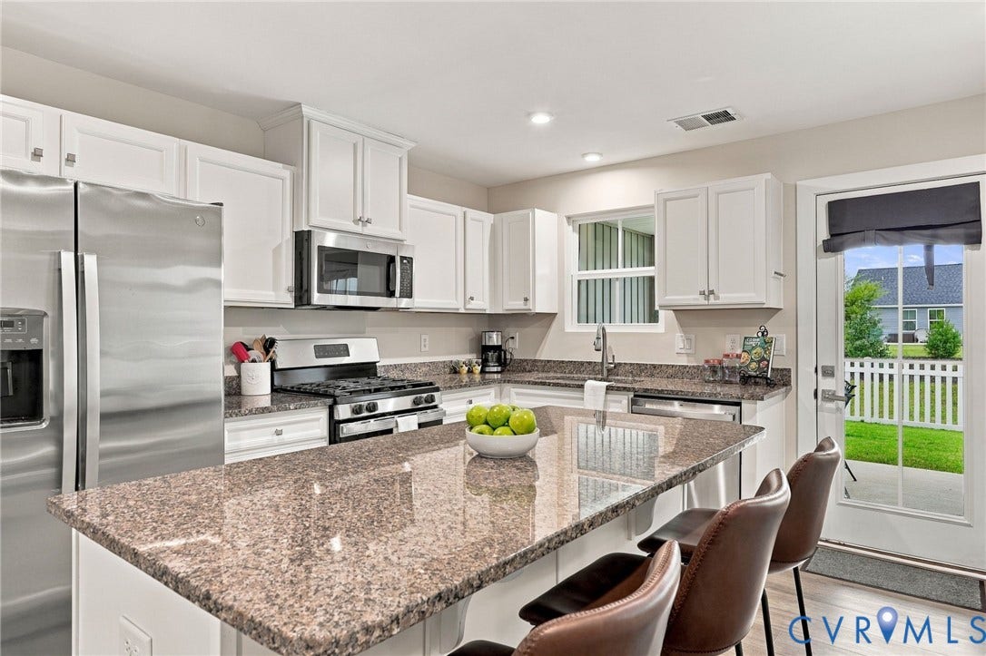 Kitchen featuring white cabinetry, stone countertops, stainless steel appliances, a center island, and glass-paned exterior door