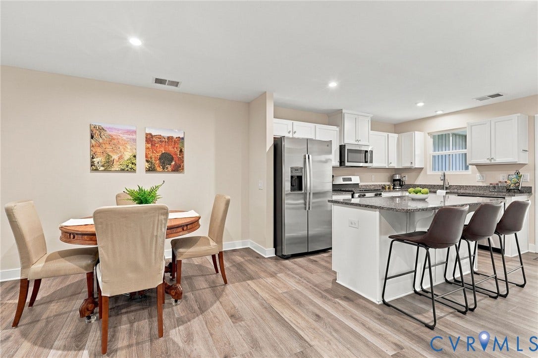 Kitchen featuring white shaker-style cabinetry, an expansive central island with stone-finish countertop, recessed lighting, and wood-finish flooring