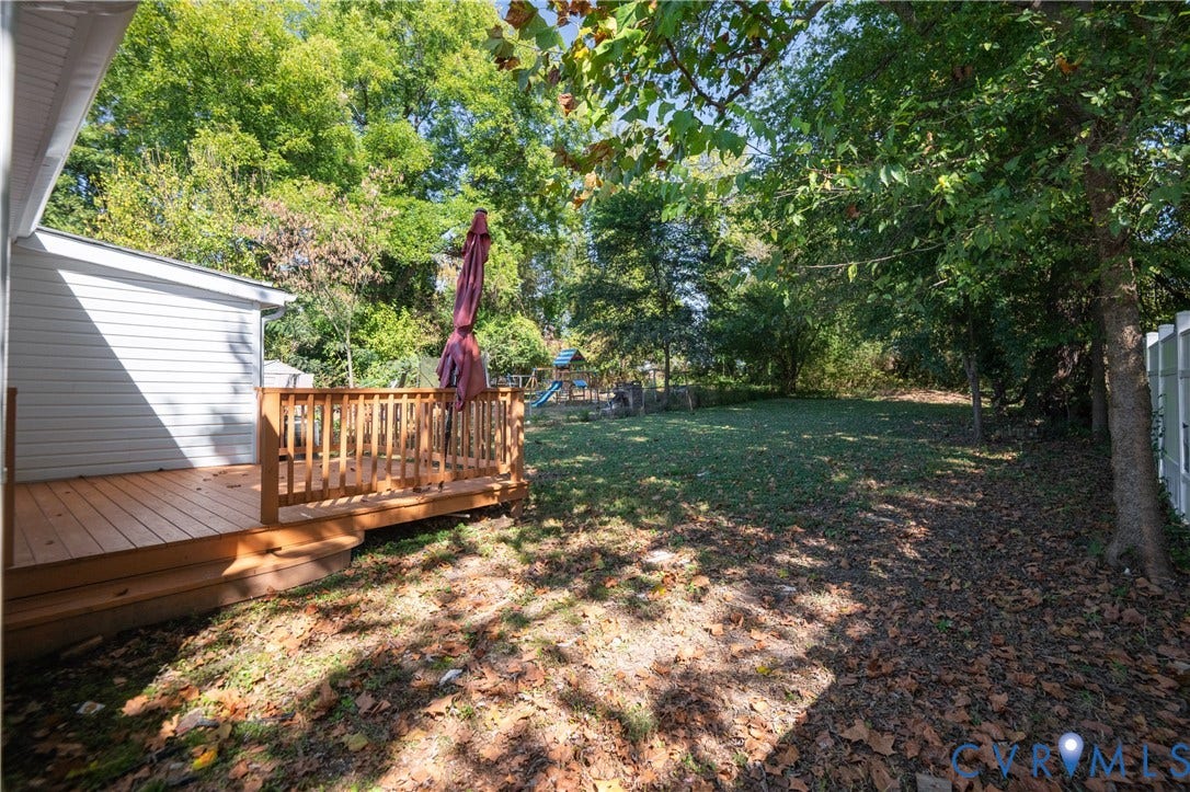 113 Spring Street, Pembroke, Petersburg, VA 23803 Rear exterior featuring a raised wood deck with balustrades, white vinyl siding, and a fenced backyard with mature trees