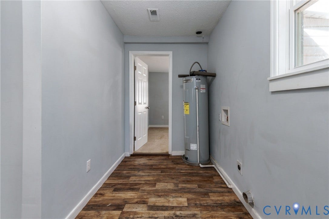 113 Spring Street, Pembroke, Petersburg, VA 23803 Utility area featuring wood-finish flooring, a vertical water heater, a window with white trim, and a six-panel interior door