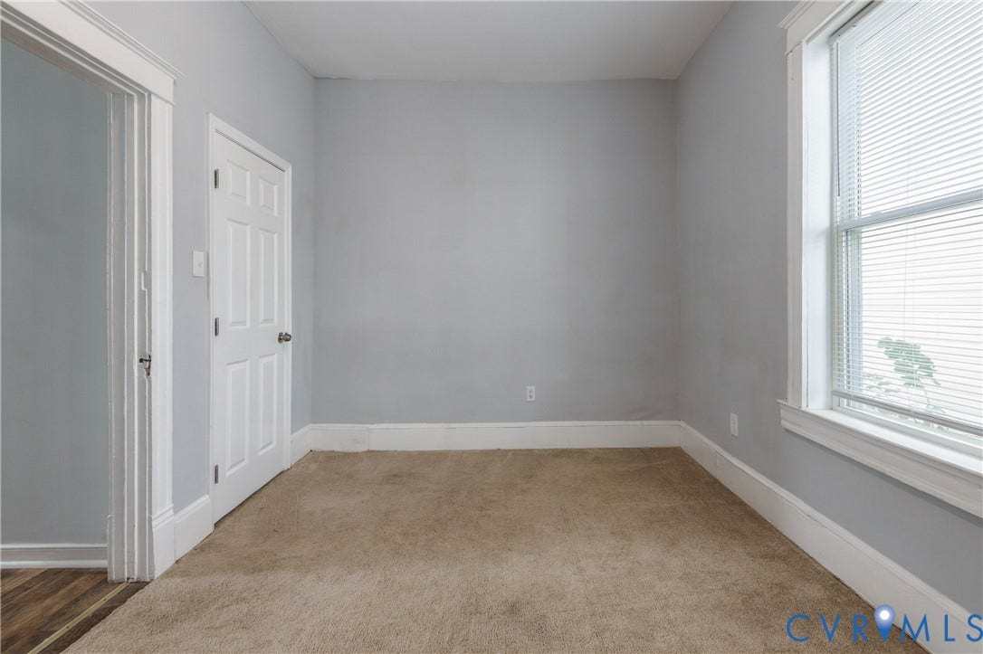 113 Spring Street, Pembroke, Petersburg, VA 23803 Neutral-toned interior space featuring light-colored wall paint, plush carpeting, a single-hung window with horizontal blinds, and a traditional six-panel interior door