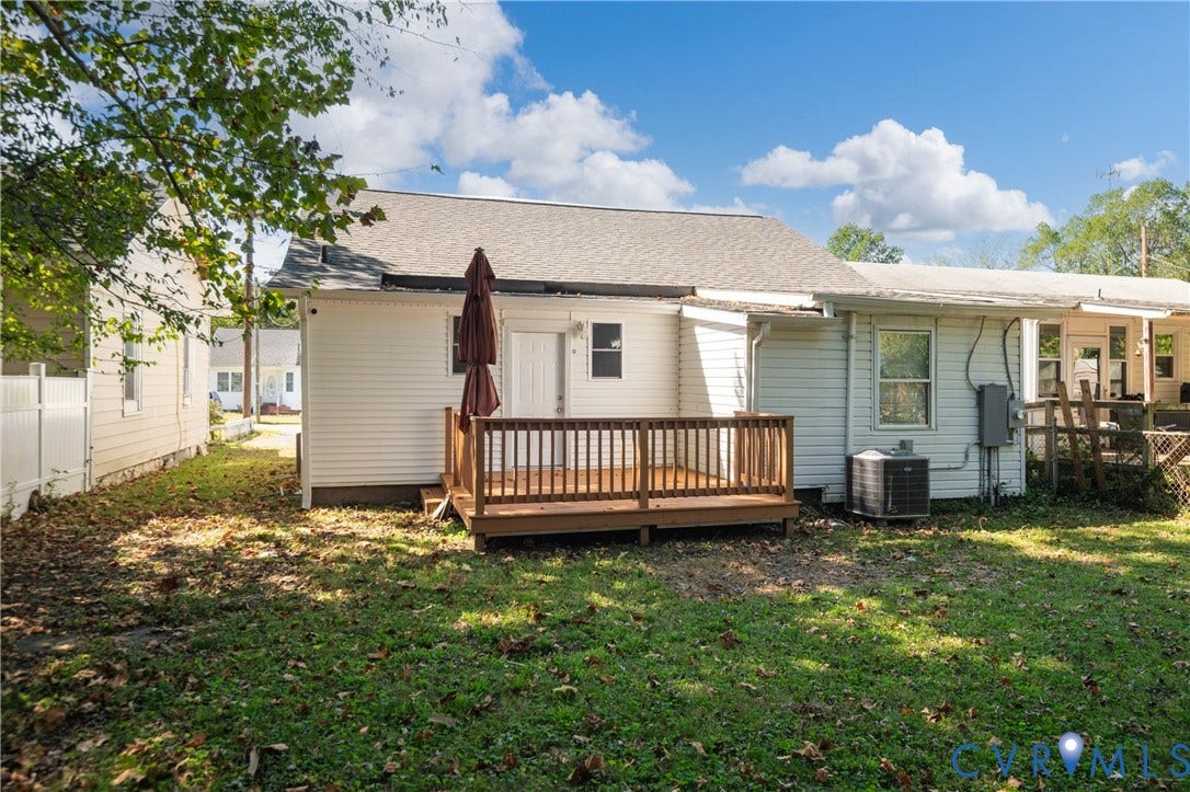 113 Spring Street, Pembroke, Petersburg, VA 23803 Rear exterior featuring white vinyl siding, a wooden deck, and a grass-covered backyard