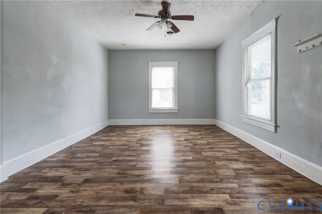 113 Spring Street, Pembroke, Petersburg, VA 23803 Interior room featuring wood-finish flooring, neutral wall paint, two windows with white trim, and a ceiling-mounted fan