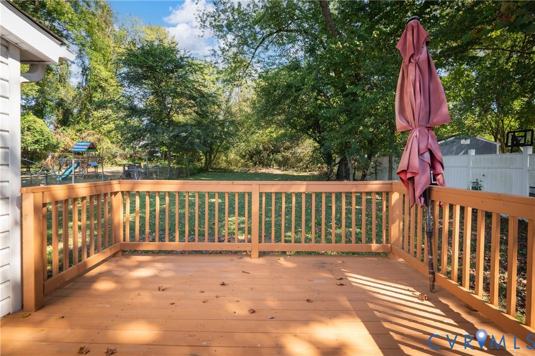 113 Spring Street, Pembroke, Petersburg, VA 23803 Raised wood deck featuring a railing and a spacious backyard with mature trees and perimeter fencing
