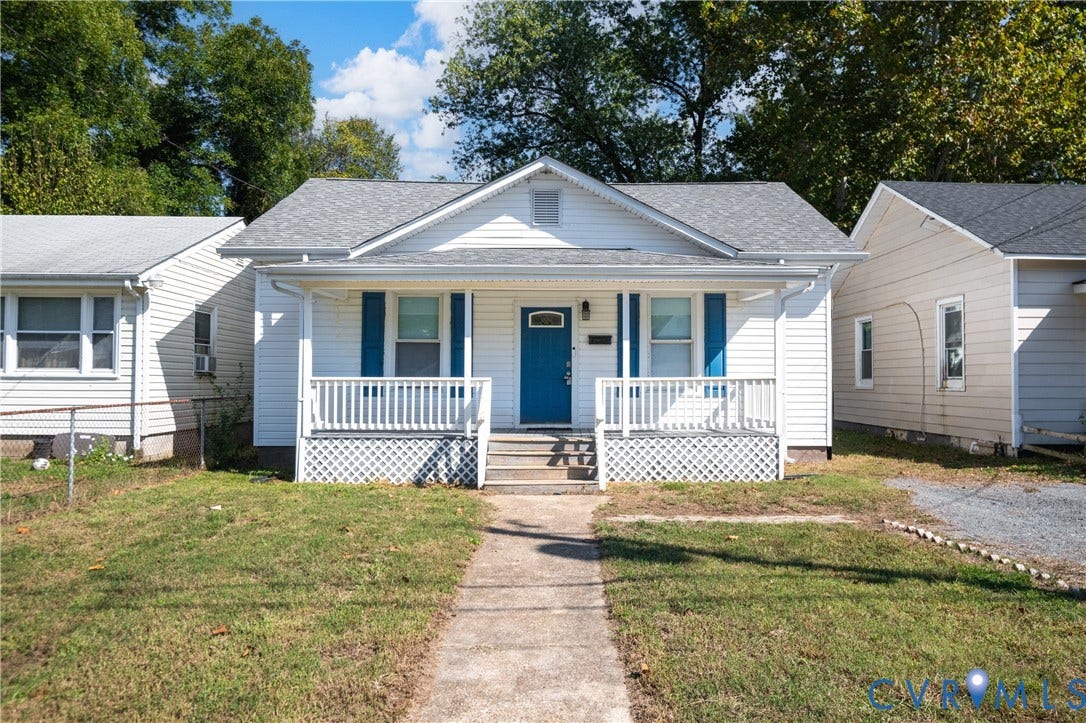 113 Spring Street, Pembroke, Petersburg, VA 23803 Gable-roof exterior with white siding, blue shutters, a covered front porch featuring a lattice base, and a central paneled door