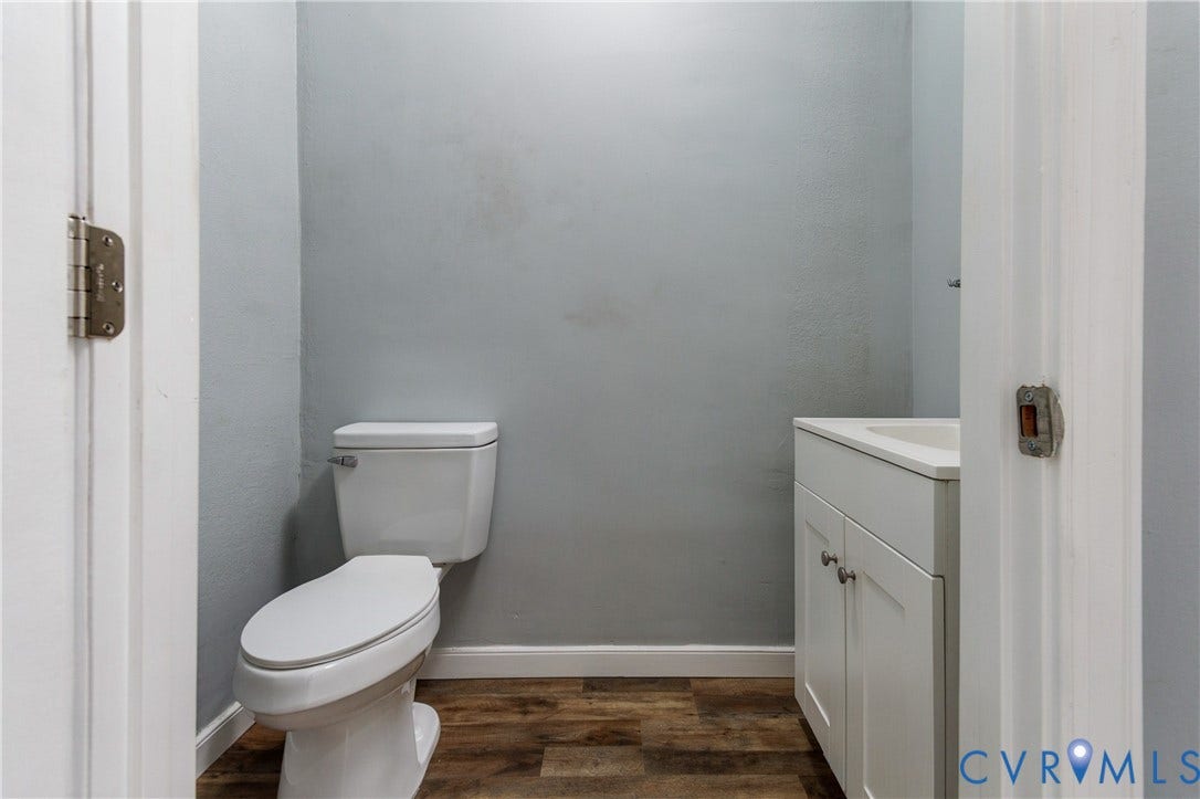 113 Spring Street, Pembroke, Petersburg, VA 23803 White vanity with an integrated countertop sink, wood-finish flooring, and a standard two-piece toilet