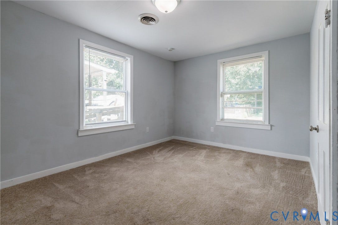 113 Spring Street, Pembroke, Petersburg, VA 23803 Neutral wall paint, carpeting, two windows with white trim, and a classic four-panel interior door