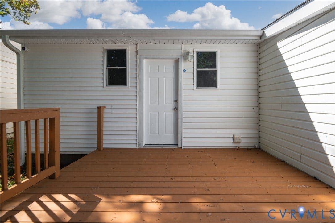 113 Spring Street, Pembroke, Petersburg, VA 23803 Exterior deck with horizontal wood-finish planks, white horizontal siding, two single-hung windows, and a panel entry door