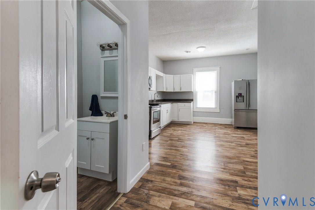 113 Spring Street, Pembroke, Petersburg, VA 23803 Kitchen featuring white shaker-style cabinetry, stainless steel appliances, and wood-finish flooring, with a separate vanity area containing a white cabinet and framed mirror