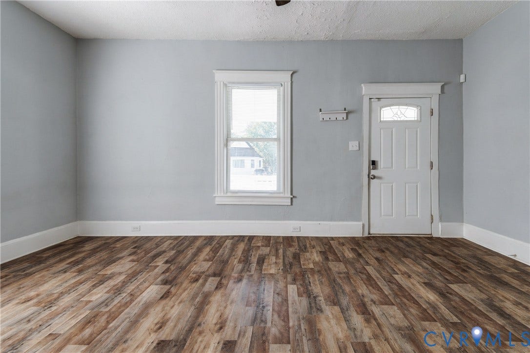 113 Spring Street, Pembroke, Petersburg, VA 23803 Interior space featuring wood-finish flooring, neutral wall tones, a single-hung window with decorative millwork casing, and a six-panel exterior door with a decorative glass insert