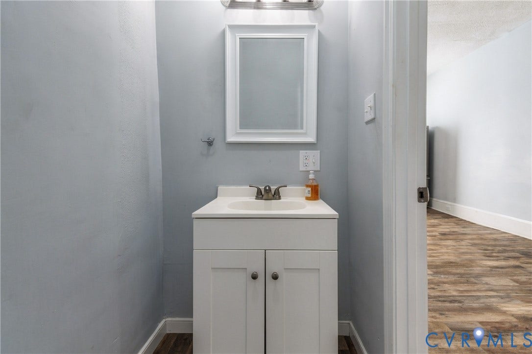 113 Spring Street, Pembroke, Petersburg, VA 23803 White vanity with an integrated countertop sink, two-handle faucet, framed wall mirror, and modern overhead light fixture