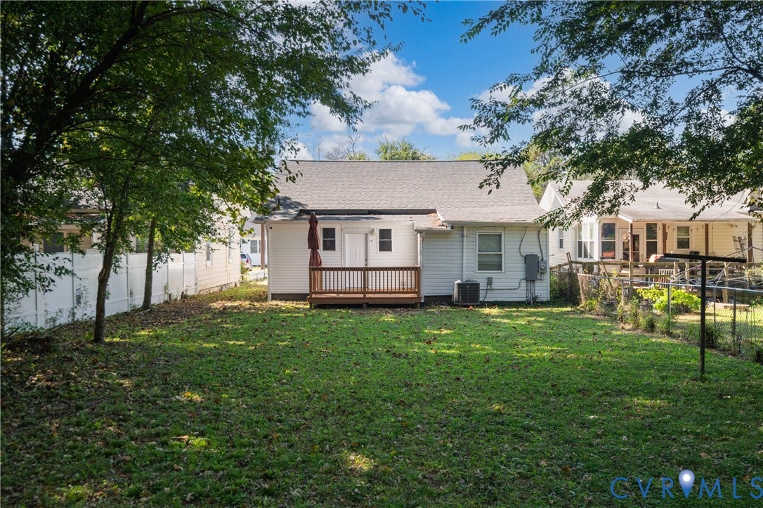 113 Spring Street, Pembroke, Petersburg, VA 23803 Backyard featuring a wood-decked patio, white vinyl fencing, grass lawn, and mature trees