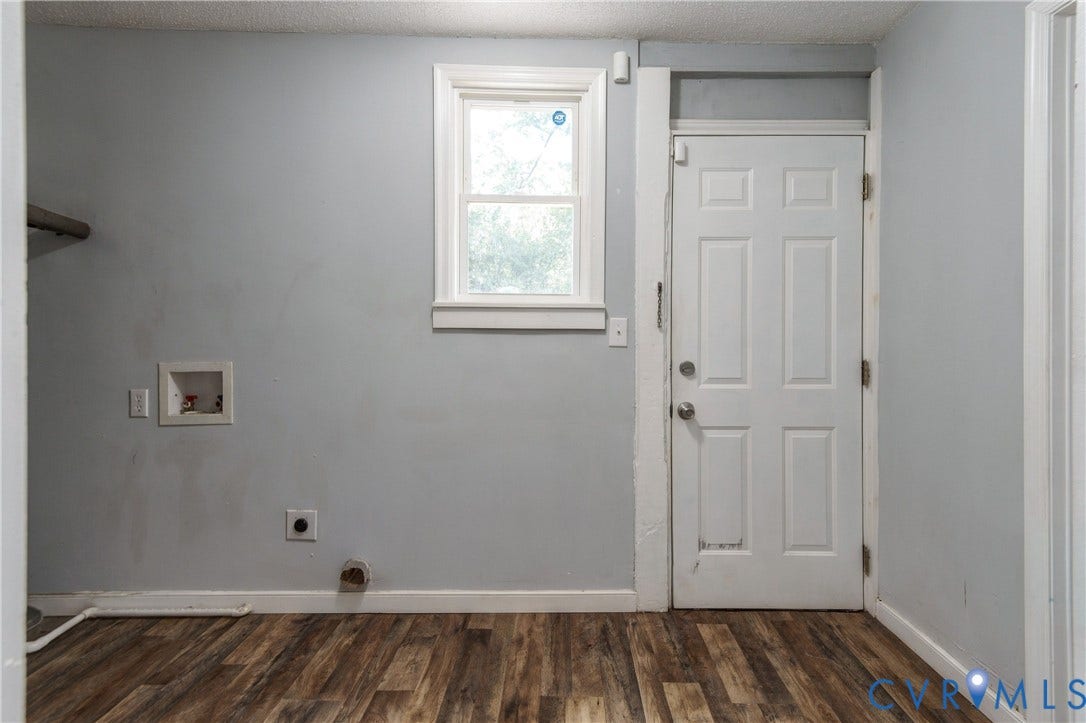 113 Spring Street, Pembroke, Petersburg, VA 23803 Utility area featuring wood-finish flooring, a single-hung window, white six-panel exterior door, and built-in wall-recessed plumbing connections