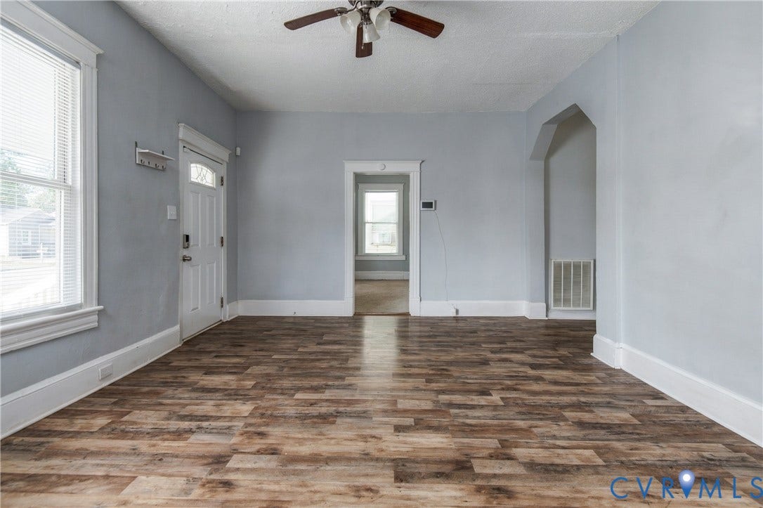 113 Spring Street, Pembroke, Petersburg, VA 23803 Interior space featuring wood-finish flooring, white door and window trim, an arched architectural opening, and a ceiling fan with integrated lighting