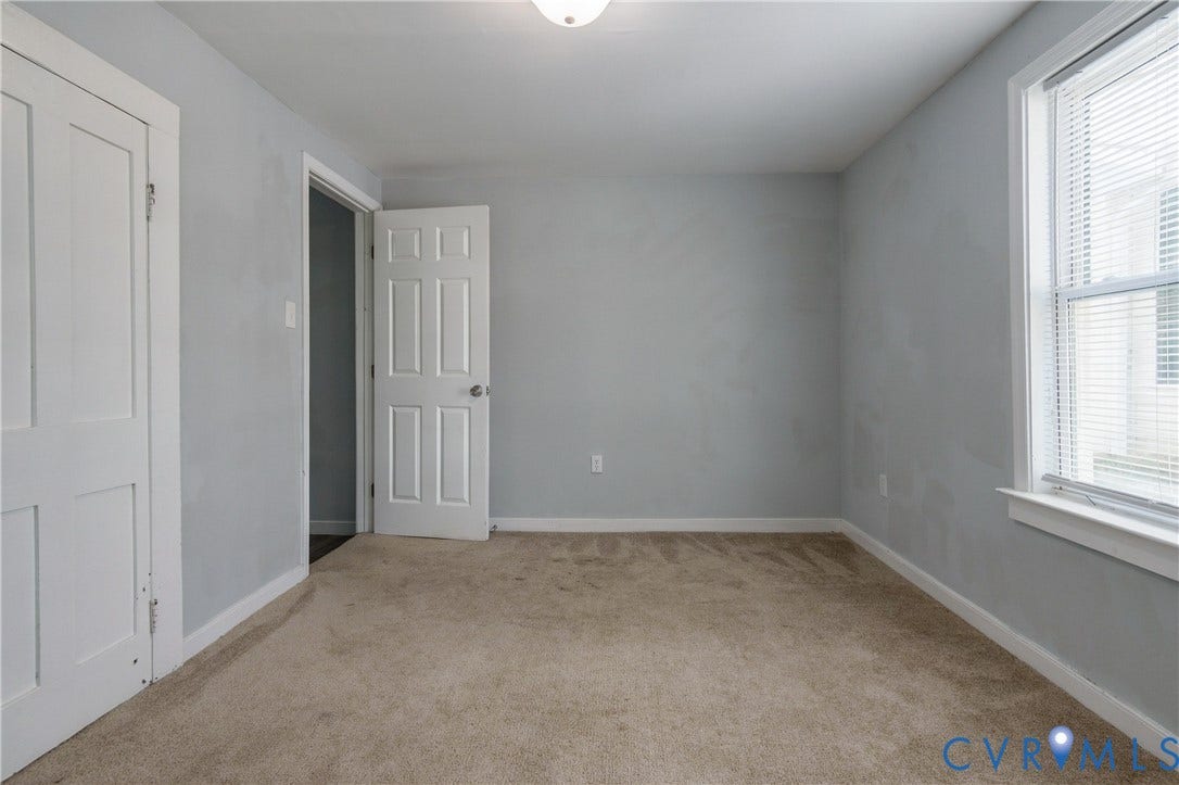 113 Spring Street, Pembroke, Petersburg, VA 23803 Interior space featuring neutral-tone carpeting, light grey wall finish, six-panel interior doors, and a double-hung window with fixed blinds