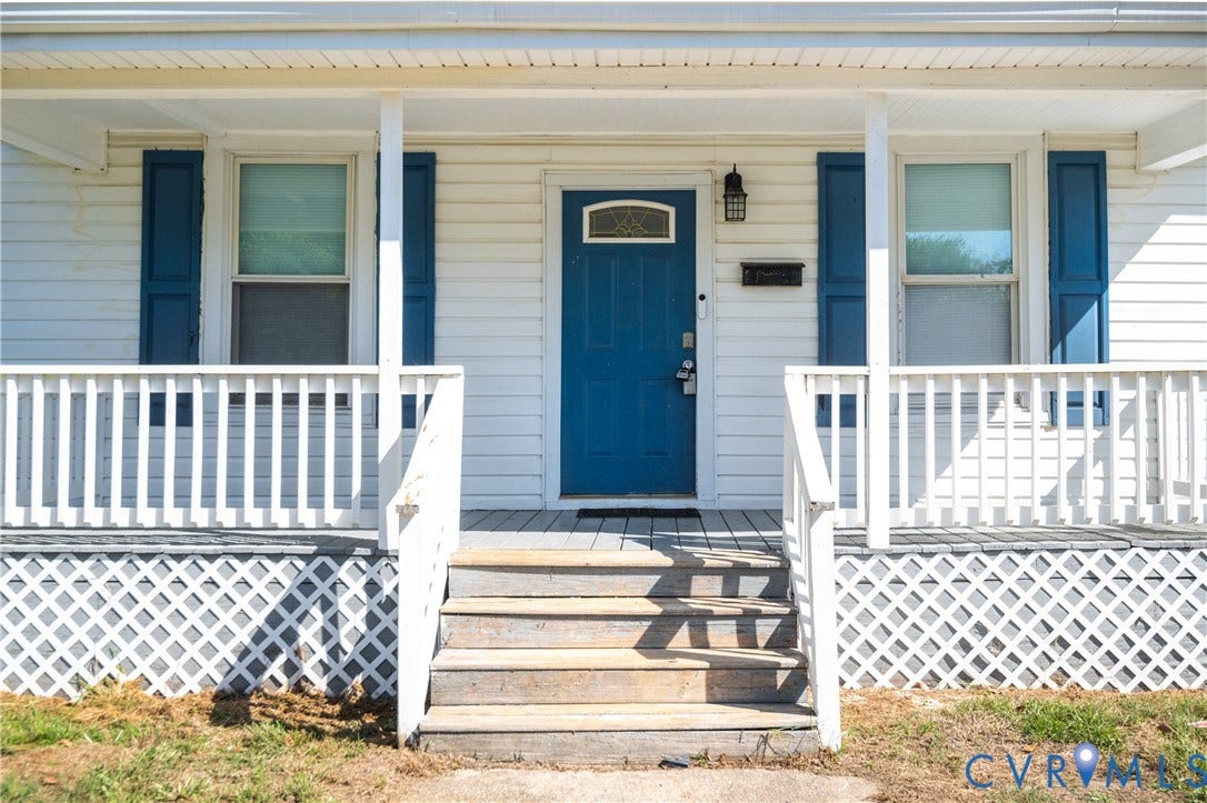 113 Spring Street, Pembroke, Petersburg, VA 23803 Covered front porch featuring white railings and lattice skirting, horizontal lap siding, blue shutters, and a solid front door with a decorative glass transom