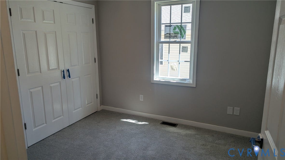 3006 Plumtree Street, South Chesterfield, VA 23834 Neutral-toned room featuring wall-to-wall carpeting, dual-panel closet doors, and a single-hung window with a grille pattern