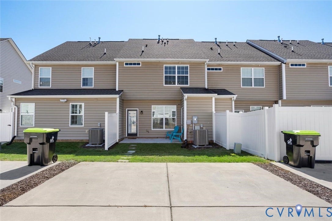 6177 Bowline Lane, Chesterfield, VA 23234 Rear exterior featuring tan siding, a dark shingle roof, white privacy partial fencing, and a concrete patio and private paved 2-car driveway.