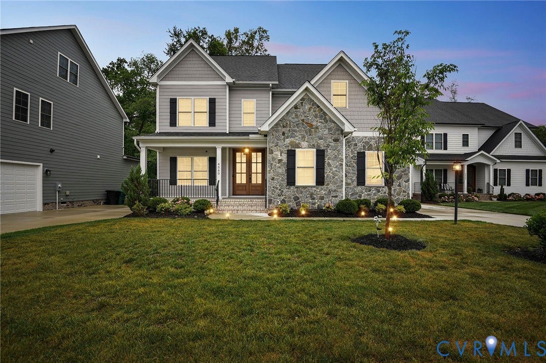 Two-story residence featuring a stone veneer and horizontal lap siding exterior, a covered front porch, decorative shutters, and a double-door entryway