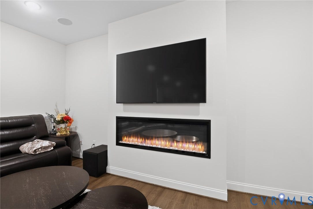 Linear built-in fireplace with a black surround, recessed ceiling lighting, and wood-finish flooring