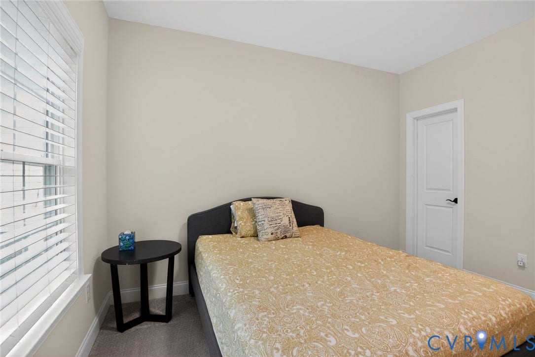 Neutral-toned walls, high-profile multi-pane window with horizontal blinds, neutral wall-to-wall carpeting, and a two-panel interior door with matte black hardware