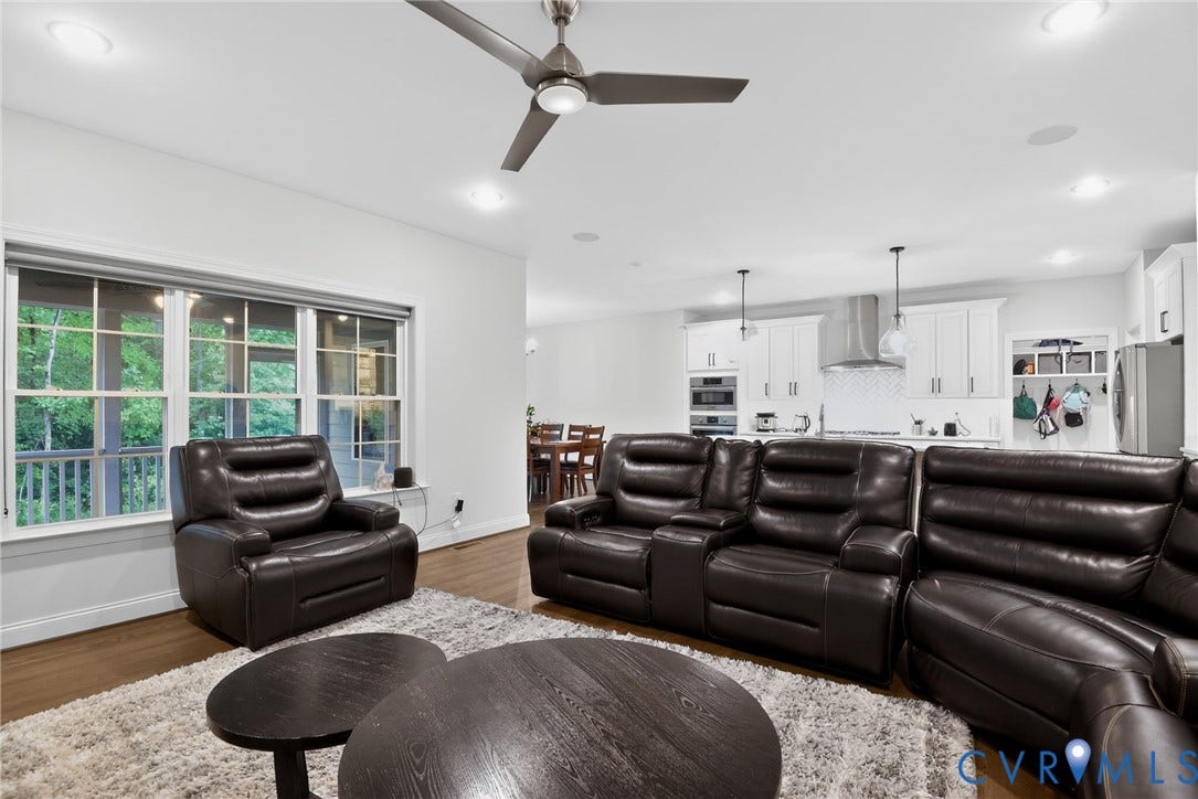 Open concept living area featuring wood-finish flooring, recessed lighting, ceiling fan, and multi-pane windows