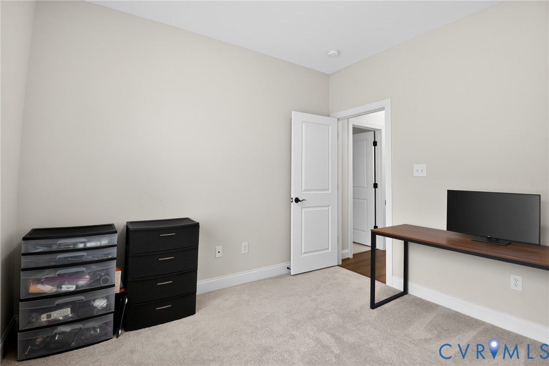 Neutral-toned walls, wall-to-wall carpeting, and a two-panel interior door with matte black hardware