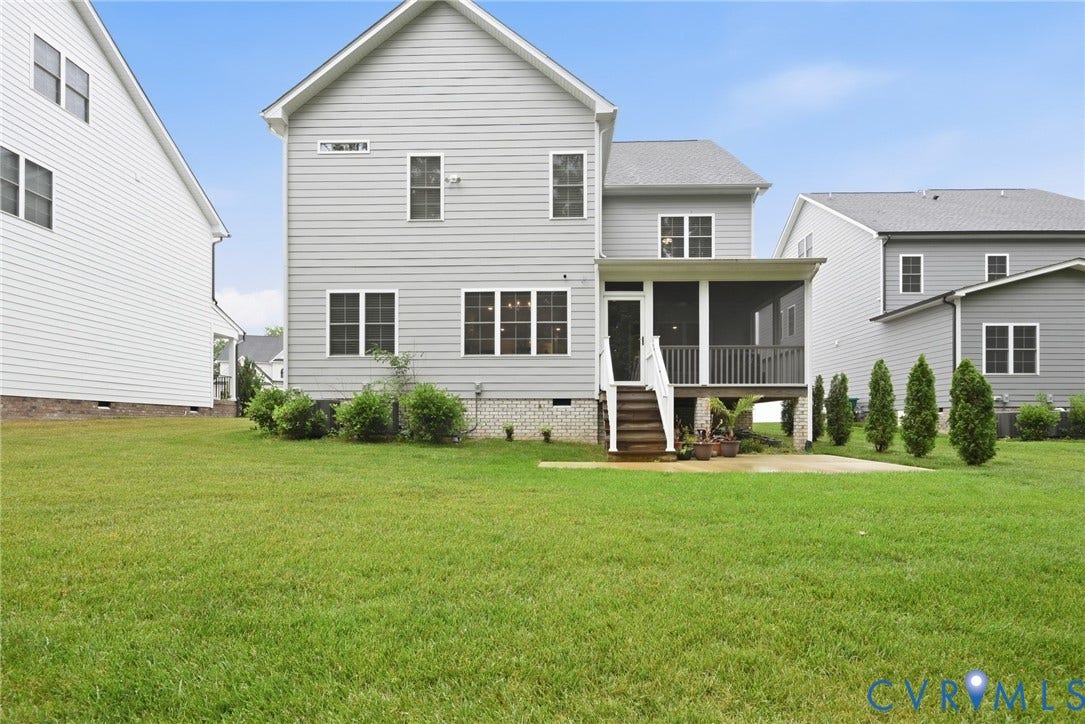 Rear exterior featuring horizontal lap siding, brick foundation, screened porch with wood-railed staircase, and expansive grass lawn