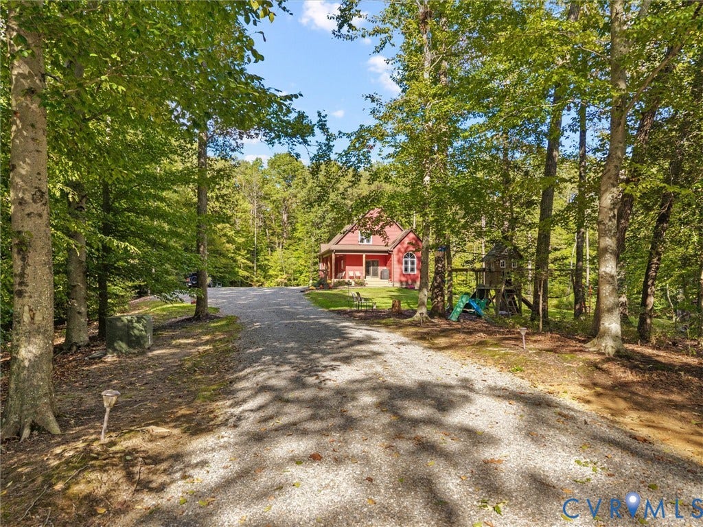 9877 Swinging Bridge Road, Taylors Grove Estates, Quinton, VA 23141 A picturesque, tree-lined driveway winds through the property, offering a peaceful approach to The Little Red Homestead. Surrounded by mature hardwoods and beautiful natural scenery, every arrival feels like a welcome escape to the countryside!