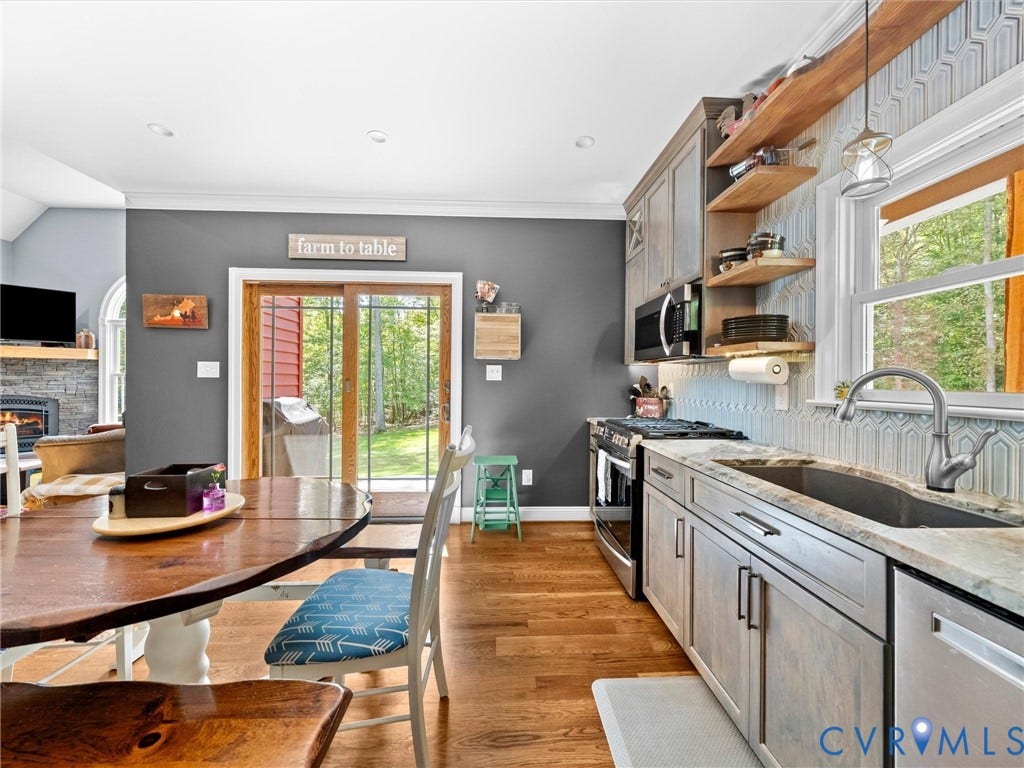 9877 Swinging Bridge Road, Taylors Grove Estates, Quinton, VA 23141 The custom kitchen offers beautiful granite countertops, stainless steel appliances, a stylish tile backsplash, and abundant cabinetry. Sliding glass doors provide direct access to the covered porch, perfect for outdoor dining and enjoying the peaceful country views!