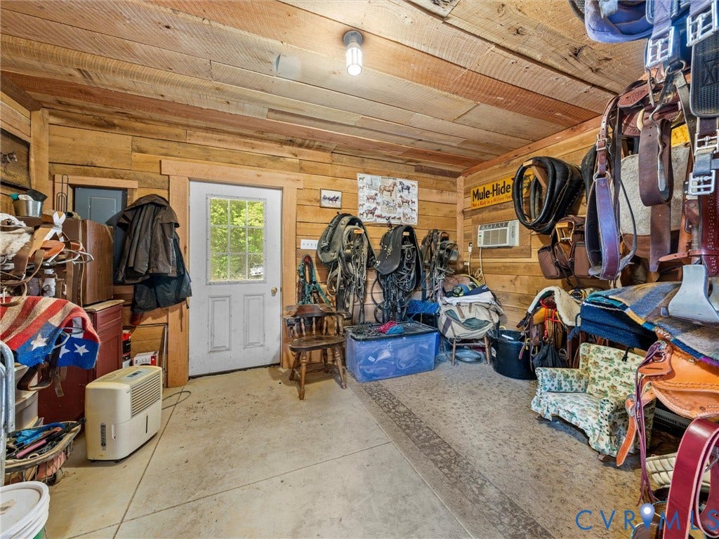 9877 Swinging Bridge Road, Taylors Grove Estates, Quinton, VA 23141 The spacious tack room features rustic wood walls and ceilings, ample room for saddles, bridles, and riding equipment, and convenient exterior access. A practical and inviting space for all your equestrian essentials!