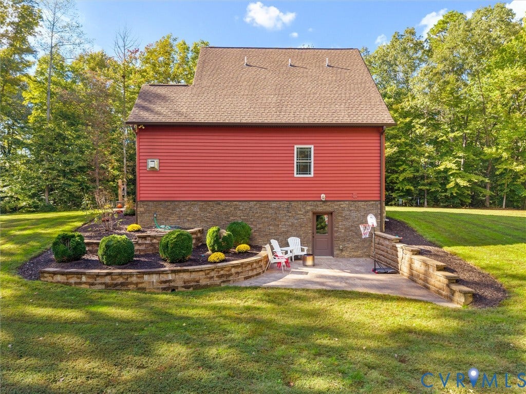 9877 Swinging Bridge Road, Taylors Grove Estates, Quinton, VA 23141 Beautifully designed outdoor living space featuring a stamped concrete patio with direct access from the walk-out basement, stunning tiered stacked stone retaining walls, and thoughtfully landscaped planting beds. A perfect setting for relaxing or entertaining while enjoying the peaceful surroundings!