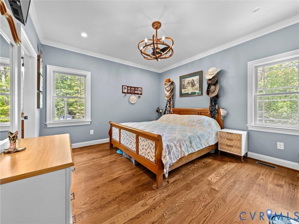 9877 Swinging Bridge Road, Taylors Grove Estates, Quinton, VA 23141 Another view of the spacious first-level primary bedroom highlights the beautiful hardwood floors, elegant tray ceiling, and abundant natural light. A peaceful retreat with two closets and a private en-suite bath!