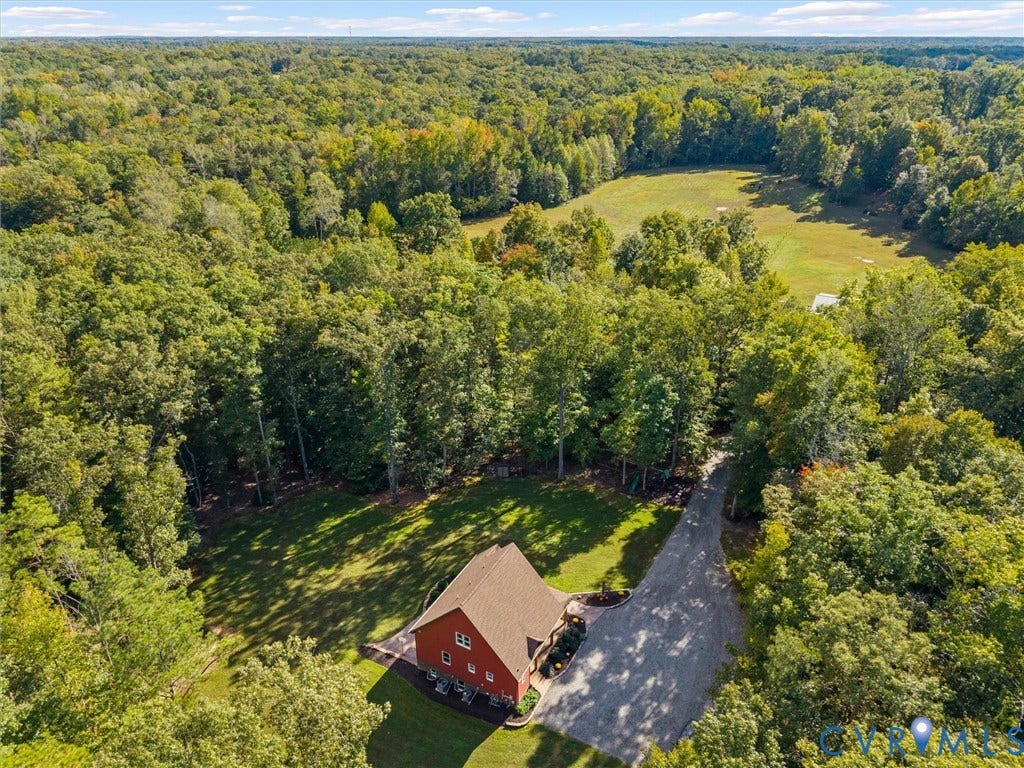 9877 Swinging Bridge Road, Taylors Grove Estates, Quinton, VA 23141 A stunning aerial perspective of The Little Red Homestead showcases the beautiful custom-built home nestled among mature trees, with a picturesque driveway winding through the property. Surrounded by rolling pastures and lush woodlands, this peaceful setting offers exceptional privacy, natural beauty, and the charm of country living!
