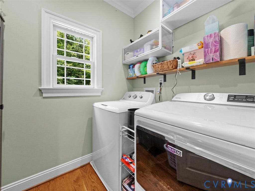 9877 Swinging Bridge Road, Taylors Grove Estates, Quinton, VA 23141 Convenient first-level laundry room featuring built-in cabinetry, countertop space for folding, and a window providing natural light. Thoughtfully designed for everyday functionality and organization!