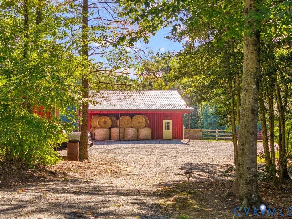 9877 Swinging Bridge Road, Taylors Grove Estates, Quinton, VA 23141 A picturesque approach through mature trees reveals the charming red horse barn, surrounded by beautiful fenced pastures and peaceful woodlands. A welcoming glimpse of the equestrian lifestyle and natural beauty this property has to offer!