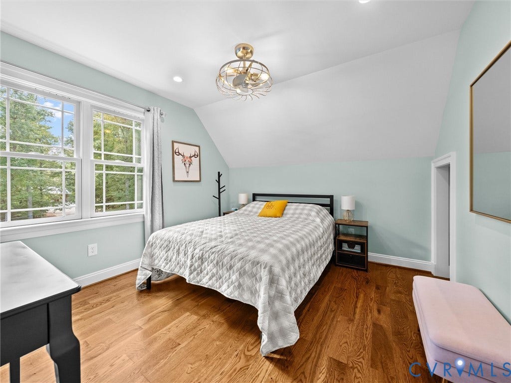 9877 Swinging Bridge Road, Taylors Grove Estates, Quinton, VA 23141 This spacious upper-level bedroom features beautiful hardwood floors, a ceiling fan, a generous walk-in closet, and large windows that fill the room with natural light while offering peaceful views of the surrounding countryside.