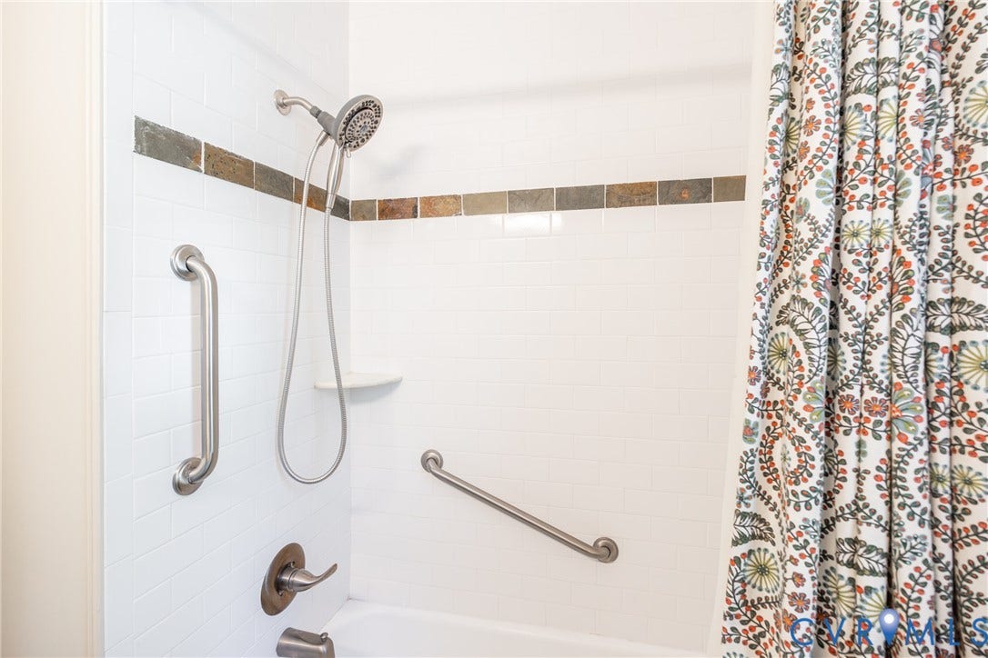 6614 Monument Avenue, Westhaven, Henrico, VA 23226 Bathtub surround featuring white subway tile, multi-tonal stone accent inlay, brushed metal plumbing fixtures, and integrated wall-mounted grab bars