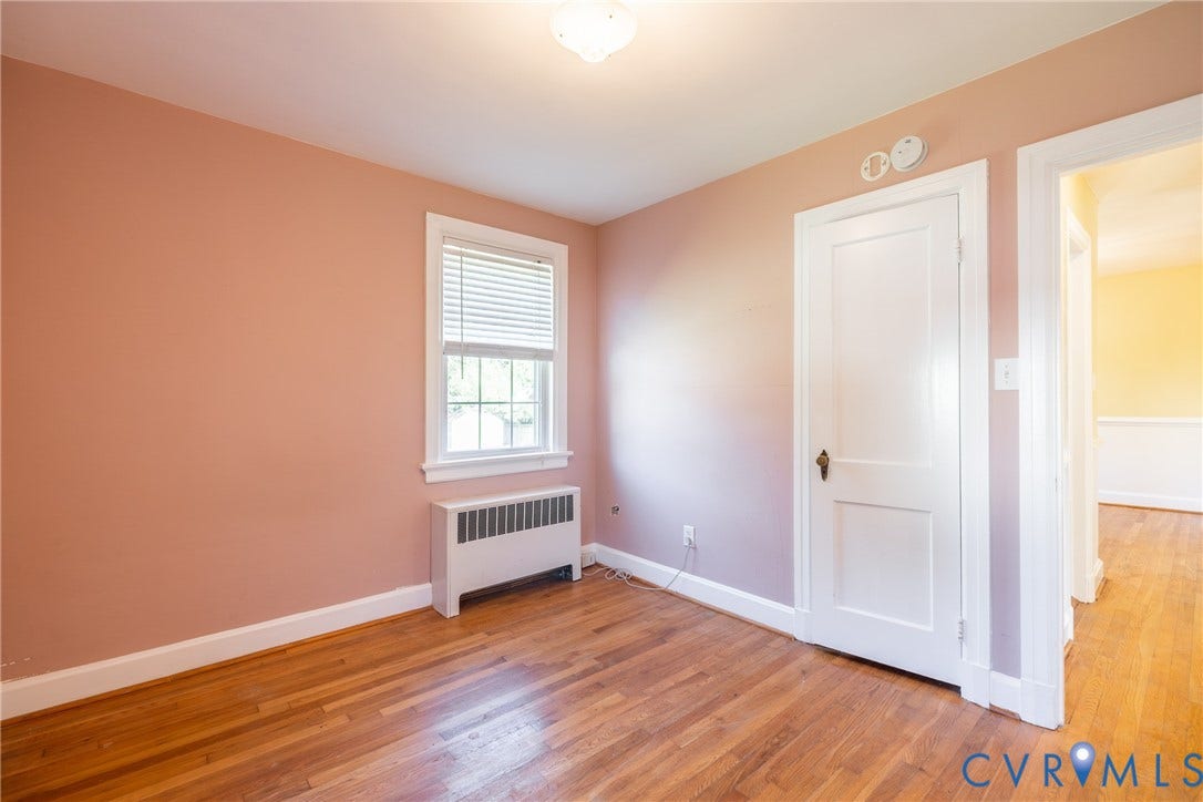 6614 Monument Avenue, Westhaven, Henrico, VA 23226 Room featuring wood-finish flooring, a single-pane window, a solid-panel door with brass hardware, and a metal radiator enclosure