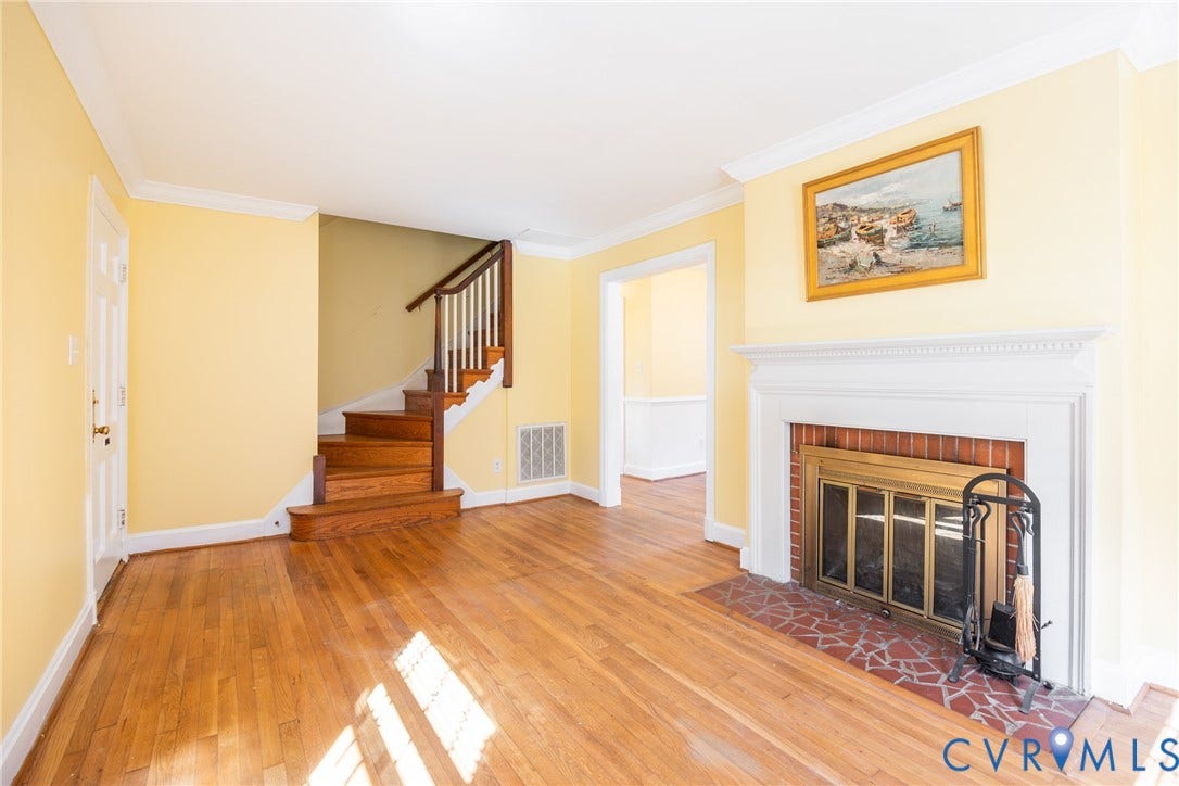 6614 Monument Avenue, Westhaven, Henrico, VA 23226 Fireplace with a brick hearth and white mantel, wood-finish flooring, and a staircase featuring a wooden handrail and balusters